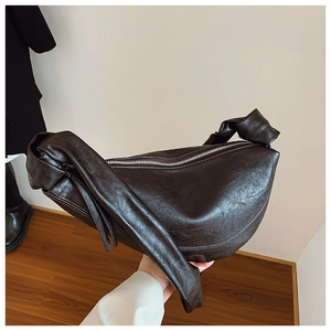 Detailed view of the dark brown leather texture and decorative knot strap on the crescent bag