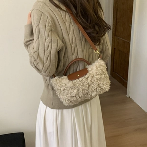 Detail of soft beige faux shearling bag with contrast brown leather trim and golden hardware