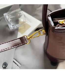 Detail of high-quality gold hardware and brown leather stitching on vintage bucket bag