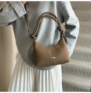 Detail of coffee-colored frosted crescent bag featuring silver metal decor and knotted strap