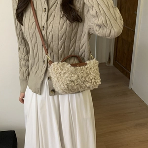 Detail of faux shearling crossbody bag with leather flap and gold metal hardware