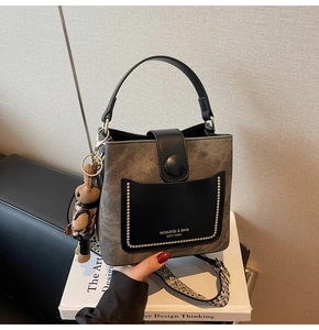 Close-up of retro bucket bag with woven strap and cute rabbit pendant charm