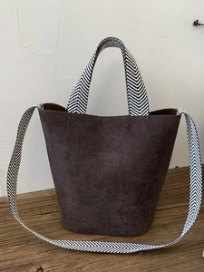 Minimalist brown suede bucket bag with stylish black and white herringbone pattern straps