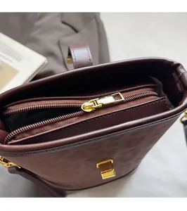 Detail of smooth metal zipper and gold hardware on deep brown frosted bucket bag