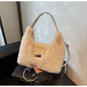 Dettaglio della borsa in ecopelliccia beige con placca logo rettangolare in metallo centrale