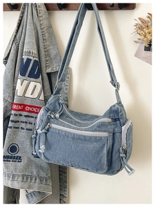 Detail of blue washed denim crossbody bag featuring utility pockets and adjustable strap