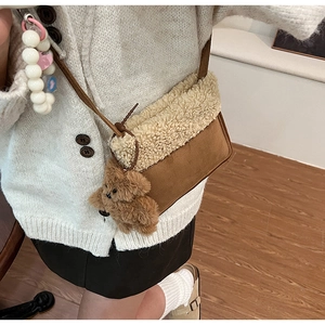 Dettaglio borsa a secchiello in camoscio marrone con bordo in shearling e orsetto