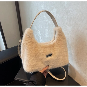 Dettaglio della texture morbida in ecopelliccia beige e logo in metallo della borsa