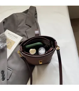 Deep brown leather bucket bag showing spacious interior with zipper pocket and long strap