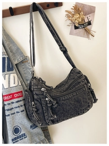 Detailed view of dark grey washed denim crossbody bag featuring multiple zipper pockets