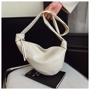 Close-up of cream crescent bag featuring a stylish knotted shoulder strap detail