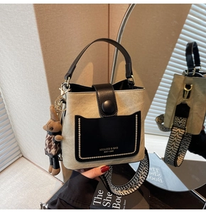 Detail of a bucket bag featuring beige fabric, black leather accents, and rabbit charm