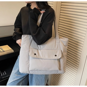 Detailed shot of a light gray quilted tote bag with double snap button front pockets