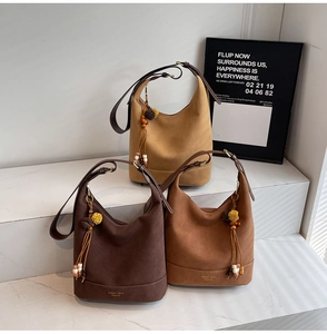 Détail de sacs seaux en daim avec glands en perles de bois sur marches en marbre