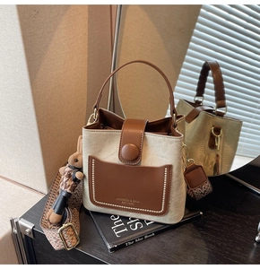 Detail of canvas bucket bag with brown leather trim, woven strap and bunny charm