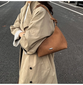 Close-up of brown textured leather hobo bag featuring silver metal buckle and knotted strap