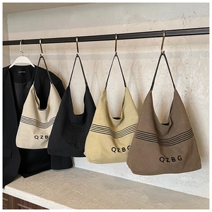 Detail view of high-capacity canvas tote bags in four colors with QZBG embroidery