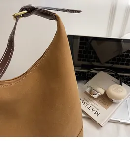 Détail du sac seau en daim mat beige avec bandoulière en cuir et fermeture éclair