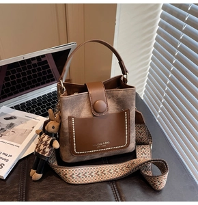 Macro shot of brown retro bucket bag with wide woven strap and rabbit plush pendant