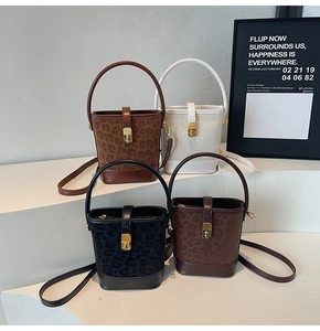 Detail of four matte bucket bags with leopard print and gold buckles on a display stand