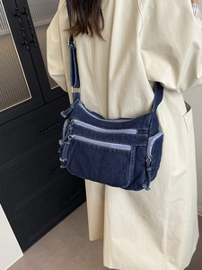 Fashionable dark blue denim crossbody bag with multi-pocket design and fringe zippers