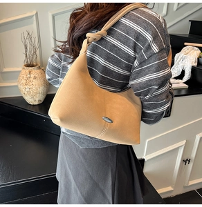 Detail view of light brown shoulder bag with a knotted strap and oval metal buckle