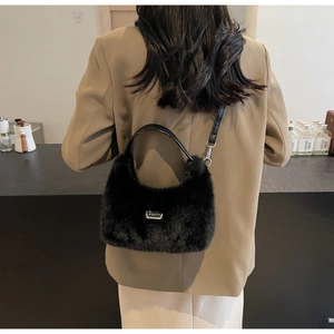 Dettaglio di una borsa in pelliccia sintetica nera con logo argento su un blazer elegante