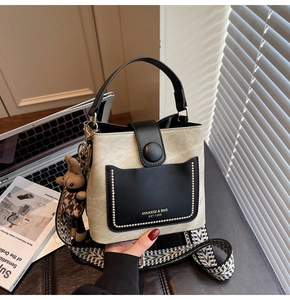 Detail of contrast bucket bag with geometric strap and plush rabbit charm accessory