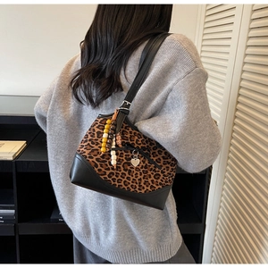 Detail of leopard print tote bag featuring black bow detail and heart pendant on shoulder