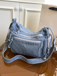 Fashionable blue denim crossbody shoulder bag with multiple zippers and wide strap