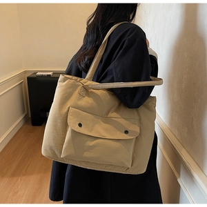 Detail of khaki large canvas shoulder bag with front flap pocket and black snap buttons