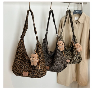 Detailed view of three large leopard print tote bags in brown, grey and yellow with plush charms