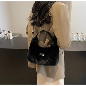Dettaglio della borsa a spalla in ecopelliccia nera con cinturino in pelle e logo