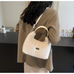 Dettaglio della borsa in peluche crema con ecopelliccia e targhetta in metallo argentato