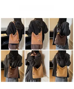 Détail d'un sac seau mat aux tons terreux avec un pendentif décoratif à pompons chic