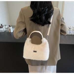Dettaglio della borsa a tracolla in peluche color crema indossata da una modella al caffè