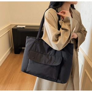 Detail of the large nylon tote bag featuring two front metal buckles and wide shoulder strap