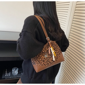 Detailed shot of leopard print shoulder bag with beaded charm and brown leather base