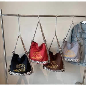 Detailed close-up of ethnic elephant embroidery and geometric straps on canvas bucket bags