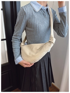 Close-up of cream-colored crescent moon bag featuring a wide knotted shoulder strap