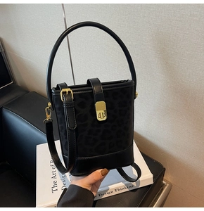Detail of black leopard print bucket bag with gold hardware on a stylish white book