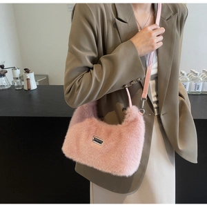 Dettaglio della borsa hobo rosa pelosa con texture in pelliccia e logo in metallo