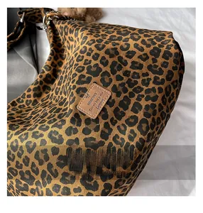 Detail of leopard print tote bag featuring a leather logo patch and metal hardware