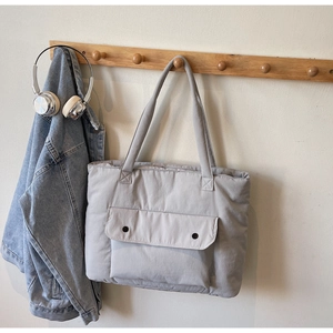 Close-up of light gray quilted tote bag with large front pocket and snap buttons