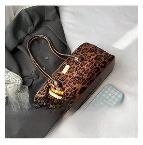 Detail of leopard print faux suede tote bag with brown leather handles and beaded charm
