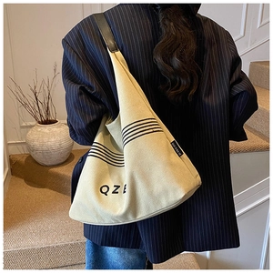 Detail of canvas tote bag with black leather straps and minimalist QZE logo print