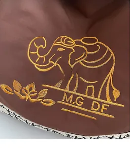 Detailed view of gold elephant embroidery and brand lettering on brown canvas bag