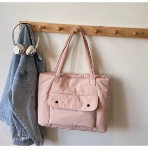 Pink quilted tote bag detail with front pockets hanging on wood hook with denim jacket