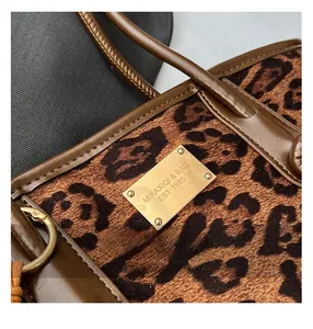Macro view of leopard print tote bag with faux pony hair texture and gold logo plate