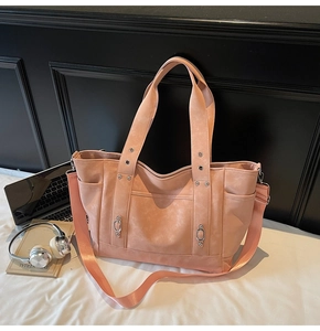 Detail view of peach pink tote bag with matte texture, rivets, and wide shoulder strap
